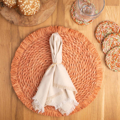 Peach raffia woven placemat scene with coasters and napkin
